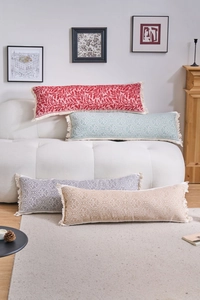 Dettaglio di cuscini jacquard multicolore con nappe su un divano in pile bianco