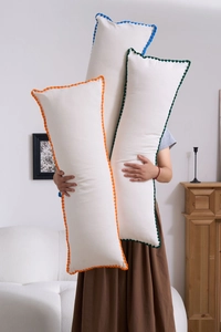 Close-up of long rectangular lumbar pillows with colorful embroidered lace edges