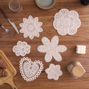 Detailed set of six handmade crochet cotton coasters in various shapes on a wooden table