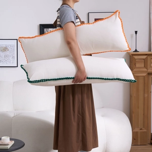 Detail of long white body pillows with colorful crochet edges in a cozy living room decor