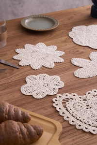 Detail shot of handcrafted white cotton crochet coasters in diverse floral and heart patterns