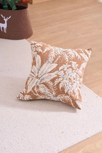 Detail view of brown chenille pillow cover featuring white tropical palm leaf patterns