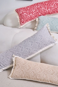Dettaglio di cuscini lombari rettangolari con motivi jacquard e nappe color crema fitte