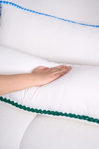 Detail of white cotton lumbar pillow showing soft texture and woven floral lace trim