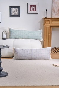 Close-up of sage green and taupe rectangular lumbar pillows with geometric fringe detail