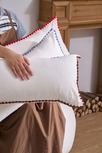 Detail of hand-crocheted wavy edges on rectangular cream cotton-linen cushion covers