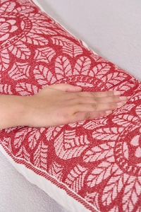 Detailed close-up of ethnic red and white geometric woven cushion with soft cotton texture