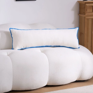 Macro shot of white fabric pillow with blue wave lace trim on a textured sofa