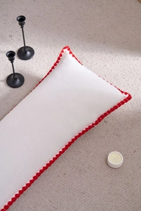 Close-up of white rectangular pillow with elegant red scalloped crochet edge detailing