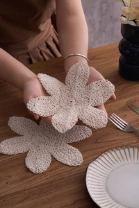 Makroaufnahme eines handgehäkelten Baumwoll-Untersetzers im Blumen-Design für Teetassen