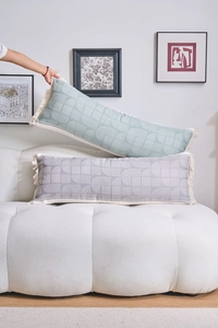 Close-up of sage green and grey lumbar pillows with geometric patterns and fringe trim