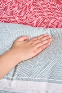 Close-up of geometric diamond pattern cushion with a hand demonstrating soft texture