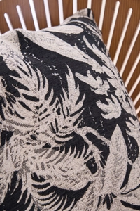 Detail of chenille jacquard throw pillow with black and cream tropical leaf patterns