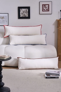 Detail of three rectangular bolster pillows with colorful wavy embroidered edges on a sofa