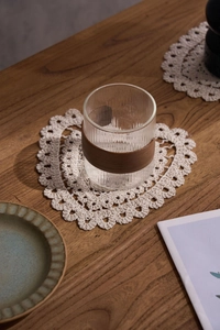 Close-up of heart-shaped cotton crochet coaster with elegant lace edges on wood
