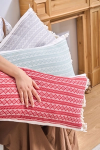 Détail d'un coussin jacquard bohème avec pompons et tissage géométrique de diamants