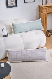 Detail of gray-green and purple long lumbar pillows with fringe and geometric patterns