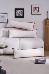 Detail of embroidered lumbar pillows with colorful wavy edges on a cozy white sofa