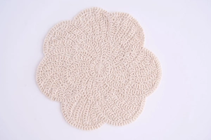 Detailed macro view of cream handmade crochet cotton tea coaster with floral wavy edges