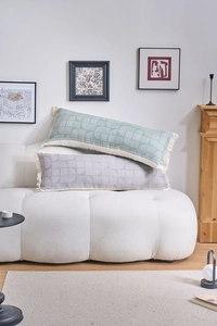 Detail of geometric pattern cushions with fringes on a textured white sofa