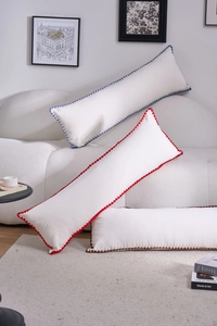 Detail of scalloped edges in blue, red and brown on cream embroidered bolster pillows