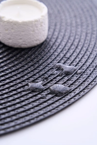 Detail of waterproof dark grey round placemat with spiral weave and water droplets