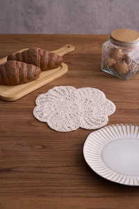 Handmade crochet cotton floral coaster on a rustic wooden table for a cozy tea time scene