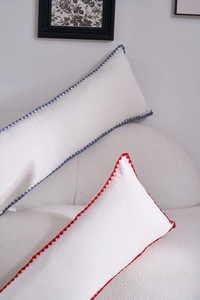 Detail of minimalist cream bolster pillow with textured fabric and crochet lace edges