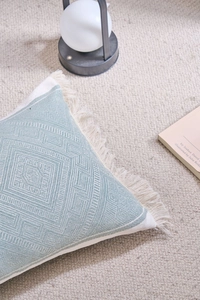 Close-up of blue jacquard lumbar pillow with geometric patterns and tassel trim edges
