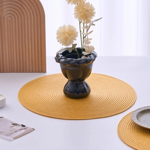 Close-up of ginger yellow circular woven placemat showing spiral heat-resistant texture
