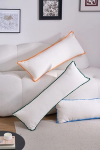 Detail of solid color rectangular lumbar pillows with colorful pom-pom fringe trim