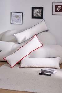 Detailed view of textured long bolster pillows with colorful wavy embroidered edges