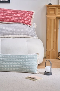 Gros plan de coussins lombaires géométriques multicolores à pompons sur un canapé