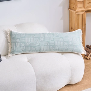 Detail of mint green lumbar pillow with geometric patterns and tassels on white sofa