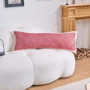 Detail of red jacquard long pillow with tassels on white cloud sofa in cozy room