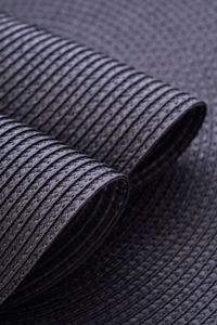 Macro shot of dark grey woven table mat showing spiral texture and flexible material