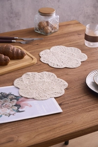 Detailed close-up of handmade floral crochet cotton coasters on a wooden table set