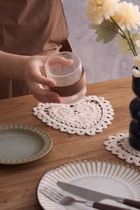 Detail of a handmade heart-shaped cotton crochet coaster with lace hollow design