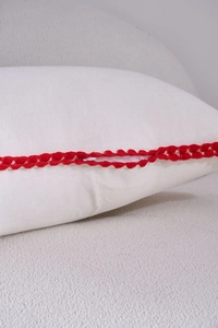 Detail of white lumbar pillow showing red crochet lace trim and invisible zipper