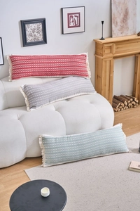 Détail de coussins lombaires tissés géométriques avec pompons sur un canapé douillet
