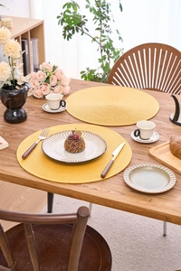 Macro shot of bright yellow round woven table mat with spiral heat-resistant texture