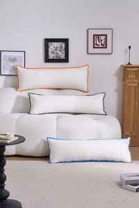 Detailed view of white rectangular bolster pillows with colorful wavy embroidered edges