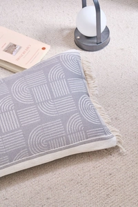 Close-up of bohemian grey and white pillow with geometric texture and tassel fringe
