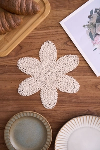 Detailansicht der handgehäkelten Baumwoll-Untersetzer in Blumenform auf dunklem Holztisch