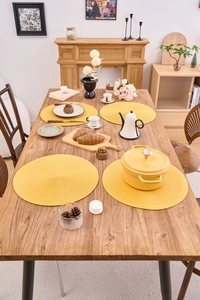 Set of four round yellow woven placemats on wooden table for heat insulation