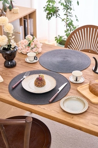 Close-up detail of dark grey round woven placemats with heat resistant spiral texture