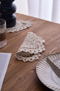 Macro detail of hand-crocheted beige cotton coaster with delicate lace hollow patterns