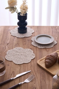 Detailed view of beige handmade crochet floral coaster with intricate woven texture on wood