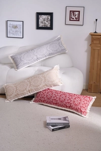 Detailed view of three long rectangular jacquard pillows with tassels in a cozy home setting