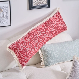 Tre cuscini lombari bohémien colorati con motivi jacquard e nappe su un divano